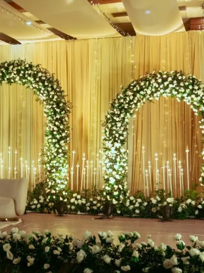 This elegant reception stage features twin floral arches and candle-like lighting, creating a symmetrical and sophisticated backdrop for the couple.