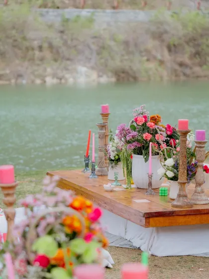 Low seating by the lake created a relaxed, 'gupshup' corner. The tables were styled with colorful candles and rustic floral arrangements to match the bohemian theme.
