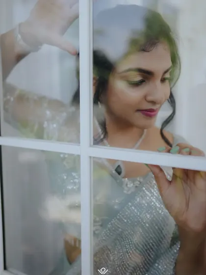 An artistic shot of a bride looking through a windowpane, creating a sense of romance and longing.