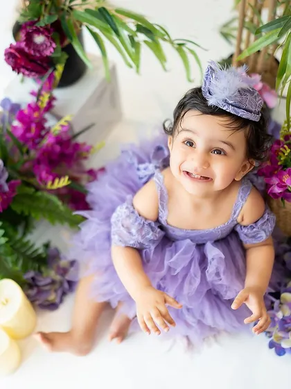A beautiful overhead shot of a baby girl in a purple dress, surrounded by flowers. This angle provides a unique and artistic perspective.