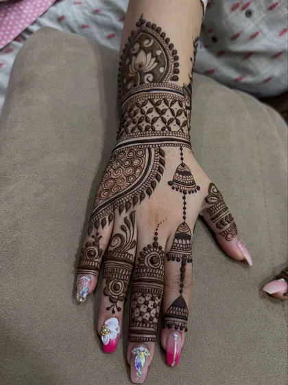 An elegant design featuring hanging 'jhumki' or earring motifs. The intricate work on the fingers and wrist creates a jewelry-like effect.