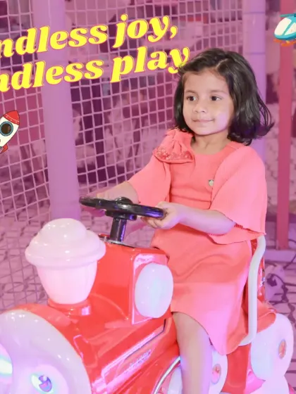 Endless joy, endless play. A little girl enjoys a ride on a bright red toy train, one of the many fun rides available for our youngest visitors.