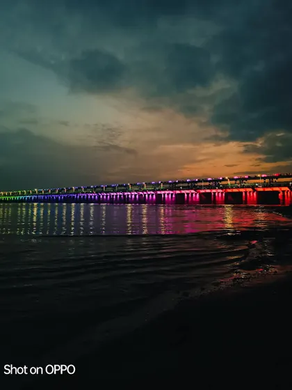 A dusk shot over a river, using the AI mode of the Oppo Reno 8 Pro. The camera's technology enhances the colors of the bridge and sunset, creating a vivid and colorful nightscape.