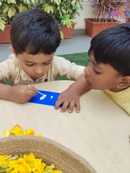 Two boys collaborate on a floral bookmark, carefully applying glue and placing petals. Teamwork and creativity are at the heart of our activities.