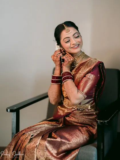 A candid moment of the bride, Aditi, smiling as she puts on her earrings, getting ready for her big day.