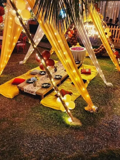 A view of the low-seating arrangement under the decorated gazebo, with cushions and a rustic table set for guests.
