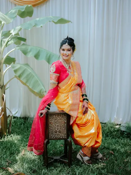 A full-length seated portrait of the bride, showcasing her beautiful smile and traditional Maharashtrian bridal look.