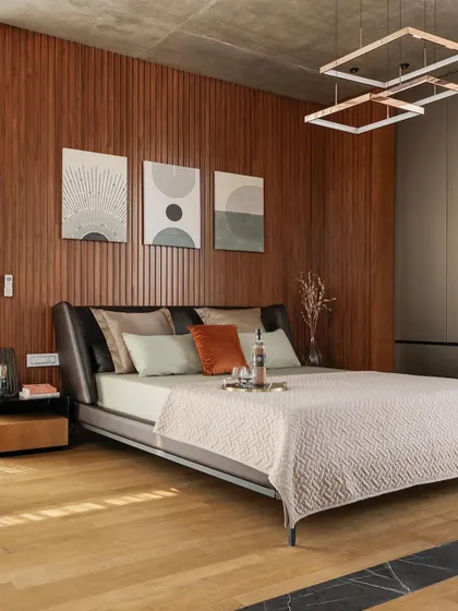 A bedroom in The Quarry House featuring a warm, fluted wood wall and modern art, creating a comfortable retreat.