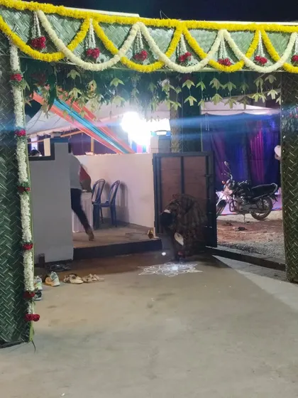 This is another style of a traditional welcome gate, or *chappra*, constructed with woven coconut leaves. The structure is decorated with garlands of white flowers and red roses, perfect for a housewarming ceremony or other traditional functions.