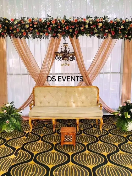 A simple yet classic stage decoration for an intimate engagement. I used elegant beige drapes, a vintage-style sofa, and a thick floral runner with a small chandelier to create a sophisticated and timeless look.