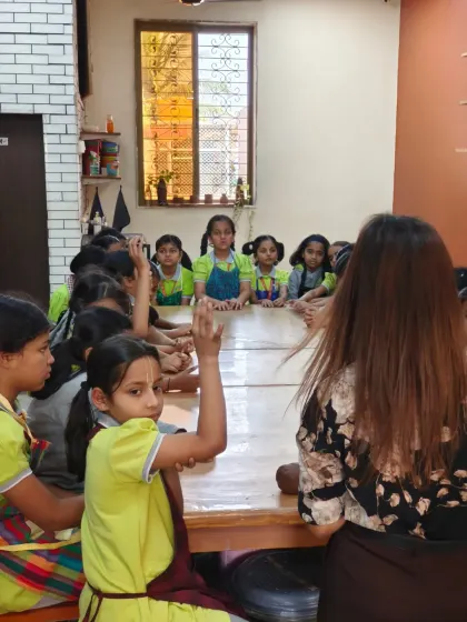 An instructor engages with a group of curious students, answering their questions about pottery. Our sessions are interactive and designed to spark a love for art.