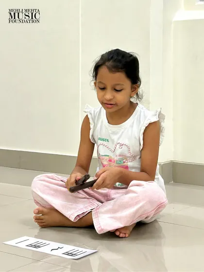A student carefully studies the notation on her flash card before playing. This exercise develops concentration and the crucial skill of sight-reading.