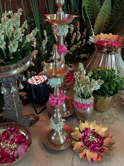 A detailed shot of the traditional decor corner, filled with brass elements, tuberoses, and rose petals, creating a fragrant and festive atmosphere.