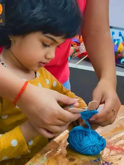 An instructor helps a student get started with her yarn wrapping. This kind of hands-on help ensures that every child can participate and feel successful.