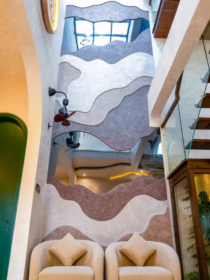 This double-height wall features a custom contour design with textured paint and tinted mirrors, creating an abstract, artistic landscape within the home.