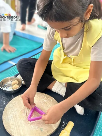 This child is making laddoos, a practical life activity that combines cooking skills, fine motor development, and cultural learning.
