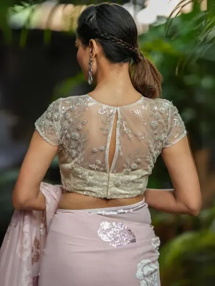 The back of this blouse features a sheer panel with delicate floral embroidery and a keyhole cutout.