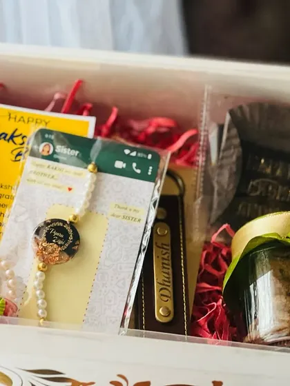 A highly personalized Rakhi gift box showing a custom rakhi with a photo, a keychain with a name, and even a screenshot of a heartfelt message.