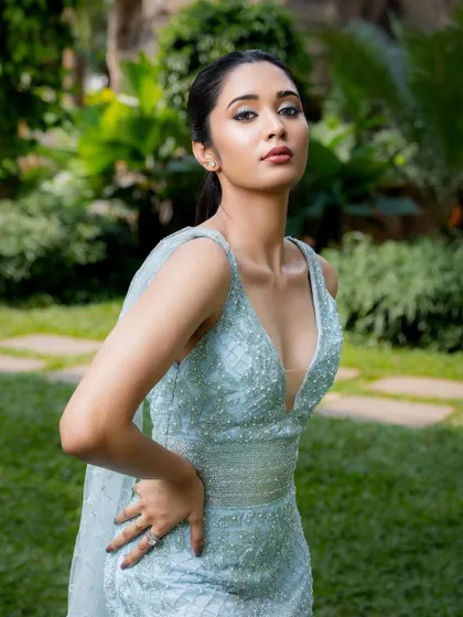 This pose highlights the flattering cut of the light blue gown, which cinches at the waist before flowing down, creating a beautiful hourglass shape.