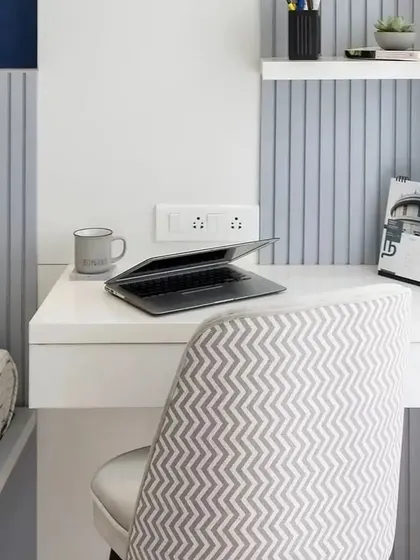 A compact and efficient workspace integrated next to the bed. The design features a simple desk, a comfortable chair, and fluted wall paneling that adds texture and visual interest.
