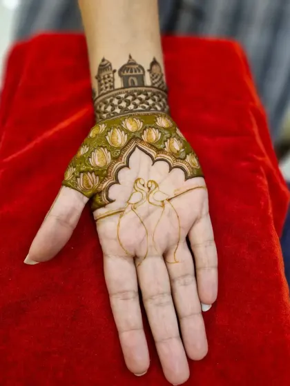 A unique Indo-Western design with two swans forming a heart shape. The wrist is adorned with a band of lotus flowers and a palace skyline.