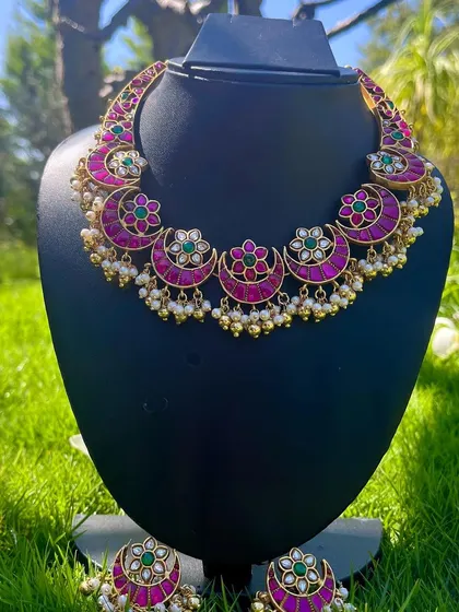 This is a classic Kemp choker with a chandbali design, featuring bright pink stones and green accents. It comes with matching earrings and is perfect for traditional events.