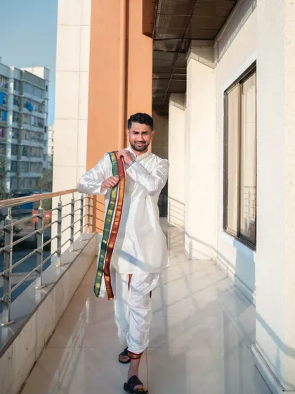 The groom, Gautam, looking sharp in his traditional white dhoti and kurta as he walks through the wedding venue.