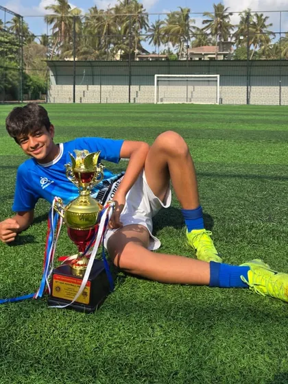 A relaxed, celebratory pose on the grass with the championship trophy.