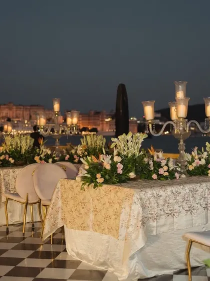 A stunning lakeside dinner setup at The Leela Palace Udaipur, showcasing long tables adorned with floral runners and candelabras. This destination event highlights our capability to create magical settings against breathtaking backdrops for exclusive corporate retreats.