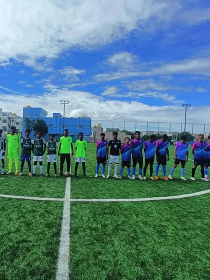 A wide shot of both teams lined up on the pitch under a beautiful blue sky.