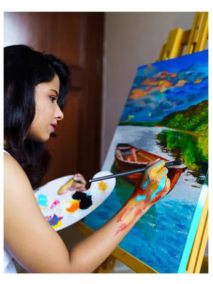 Me at my easel, working on the boat landscape painting. My paint-splattered hand and palette show the messy, hands-on process I love.