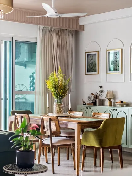 A full view of the dining area in the 'Tatvam' project, showcasing the mint green crockery unit, wooden dining set, and the blush pink ceiling that ties it all together.