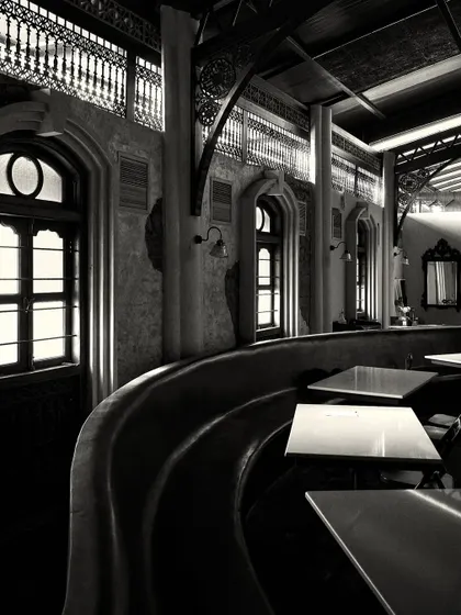 A long, curved banquette provides seating along the wall, punctuated by arched windows that bring in natural light.