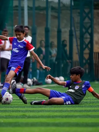 A player makes a crucial slide tackle. We teach our players to play with grit and heart in every match.
