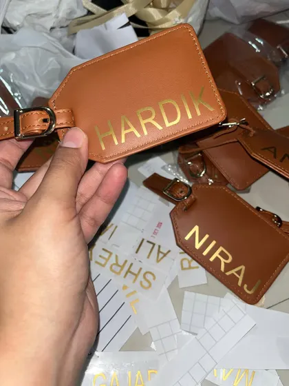 A behind-the-scenes look at our personalization process. Here, we are applying gold foil names to leather luggage tags, ensuring each gift is perfectly customized for corporate events or wedding favors.