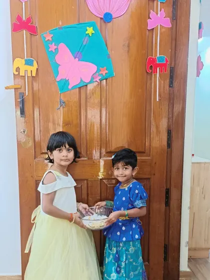 A duplicate of a previous image, showing two girls sharing 'Yellu Bella' for Makar Sankranti.
