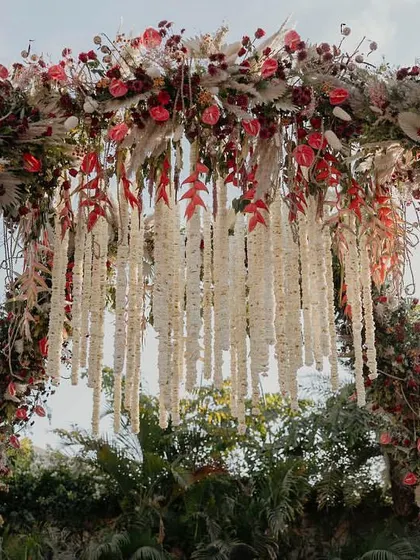 A closer look at the intricate floral work on this grand mandap. We layered different textures and shades of red with dried pampas grass and a cascade of tuberose garlands for a truly opulent look.