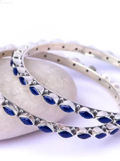 A pair of elegant silver bangles with marquise-shaped blue enamel work. These can be stacked or worn individually for a pop of color.