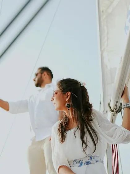 A dynamic pre-wedding photo of a couple on a sailboat, capturing the sense of adventure and the open sea.