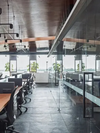 The open-plan workspace in the 'Terrace Office' is designed to maximize natural light and views. Low partitions ensure that every employee has a connection to the windows, which look out over a lush green landscape, promoting a sense of well-being.