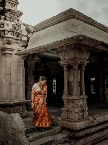 A solitary, graceful portrait of the bride in her traditional saree, walking through the historic temple grounds.