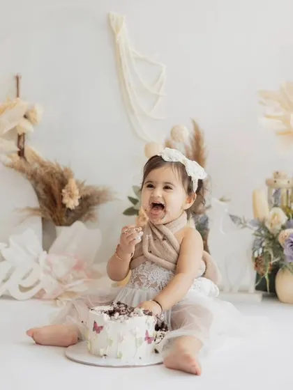 A moment of delicious discovery during a boho-themed first birthday cake smash. The neutral palette with pops of lavender creates a sophisticated yet sweet look.