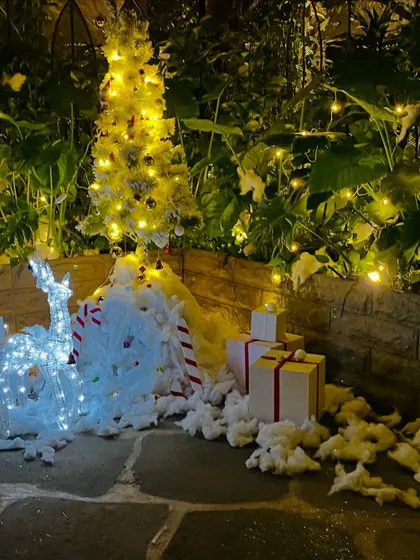 A detailed shot of the illuminated reindeer and the base of the tree, surrounded by faux snow and gift boxes.