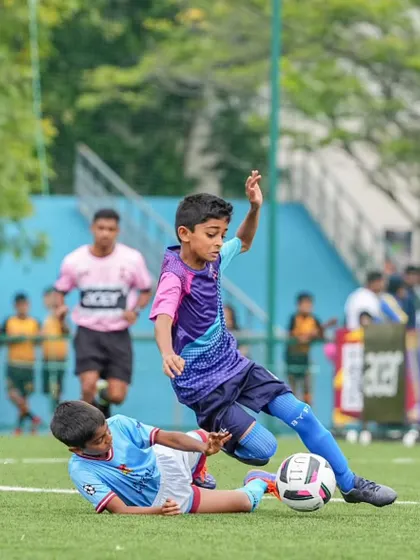 A U11 player skillfully evades a sliding tackle during the DPDL Super Cup. Agility and quick thinking are crucial skills we develop.