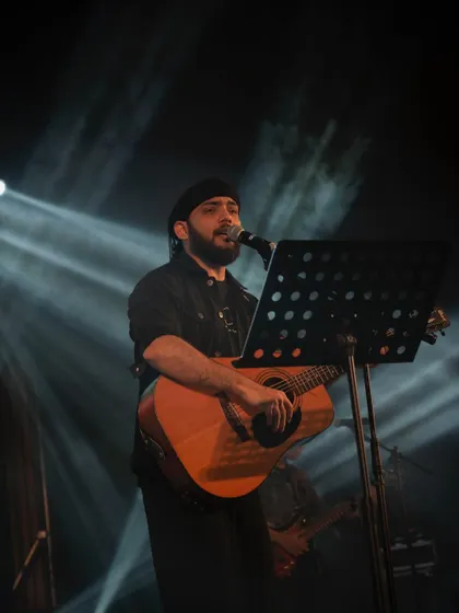A quiet moment during a soulful acoustic performance. Sometimes the most powerful songs are the ones that are stripped down, just a voice, a guitar, and a spotlight.