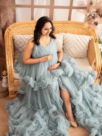 A full-length portrait showing the dramatic ruffles of a dusty blue gown, as the mom-to-be sits elegantly in our boho studio.