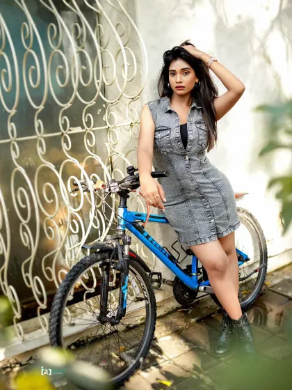 An urban portrait with a casual, sporty edge. The bicycle prop and denim dress create a youthful and energetic feel, perfect for a lifestyle-oriented photoshoot.