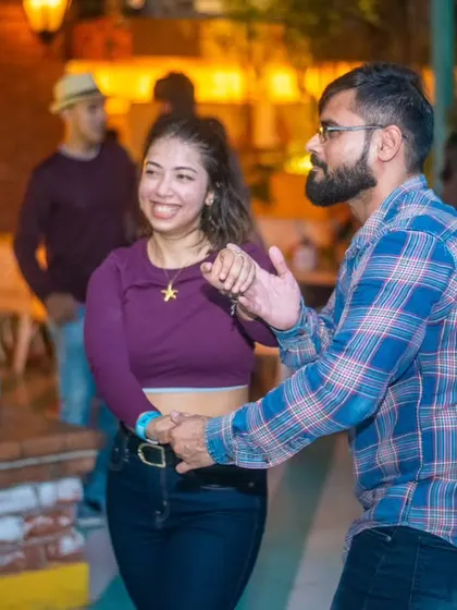 A smiling couple enjoying a dance. The plaid shirt and purple top add a splash of color to the floor.