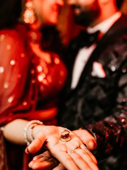 A close-up, artistic shot focusing on the engagement rings held in the couple's hands, symbolizing their new commitment.