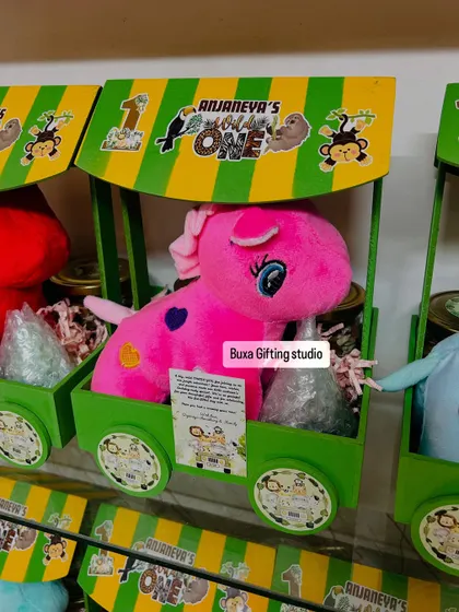 Welcome to the jungle! This "Wild One" birthday hamper comes in a green and yellow cart, filled with a soft toy, coconut cookies, trail mix, and a jungle-themed candle.